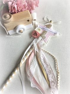 some pink flowers are sitting next to a wooden toy truck and thread spools