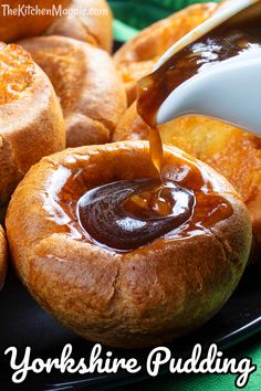 a person pouring sauce onto some bread rolls on a plate with the words yorkshire pudding