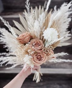 a person holding a bouquet with flowers and feathers on it's head in their hand