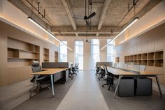 an empty office with desks and shelves in the center, along with ceiling fans