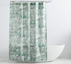 a shower curtain with a green and white floral pattern on it next to a bathtub