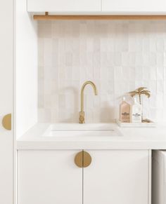 a white kitchen with gold faucet and sink