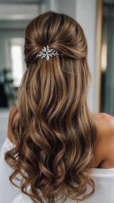 the back of a woman's head with long wavy hair and a crystal brooch