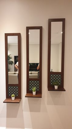 three mirrors mounted to the wall with planters on each one and a couch in the background