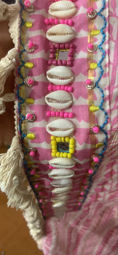 a pink and white dress with lots of buttons on the front, along with other beads