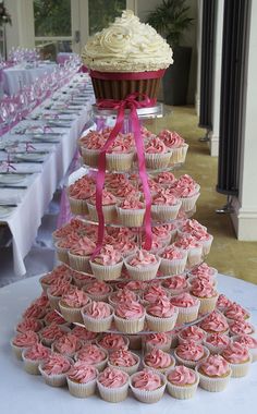 cupcakes are stacked on top of each other in front of tables with white tablecloths