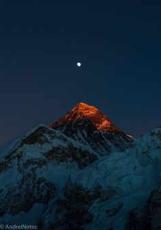 the moon is setting on top of a snowy mountain with snow covered mountains in the foreground