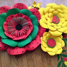 two paper flowers sitting on top of a wooden table