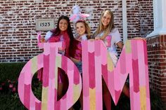 three girls are posing in front of the letters dm and m with their name on it