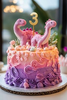 a birthday cake decorated with pink and purple frosting, two dinos on top