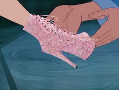 a pair of pink glitter high heel shoes being held by someone's hand in the water