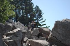 two people standing on top of large rocks with trees in the background