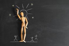 a wooden doll is standing in front of a chalk drawing on a blackboard with stars