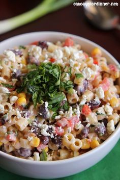 a white bowl filled with pasta salad and garnished with parsley on top