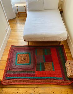 a bed sitting on top of a wooden floor next to a white pillow and blanket