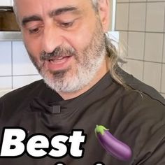 a man with long hair and beard wearing a chef's uniform holding a purple pepper in his right hand