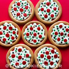 six decorated cookies with white frosting and red, green, and black toppings