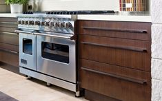 a stove top oven sitting inside of a kitchen next to wooden cabinets and counter tops