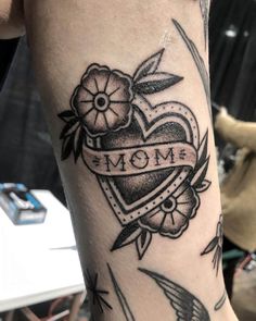 a woman's arm with an arrow and heart tattoo on it, which reads mom