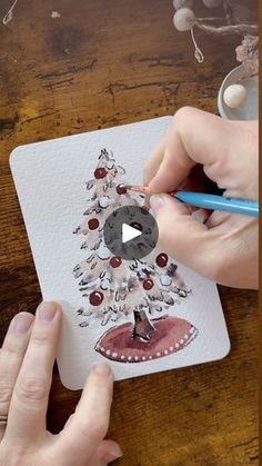 someone is drawing a christmas tree with colored pencils on a piece of white paper