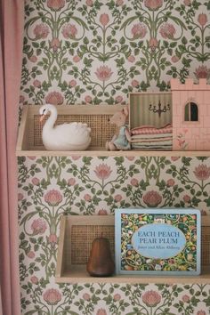 two shelves with books and toys on them in front of a wallpapered background