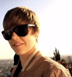 a young man wearing sunglasses on top of a building