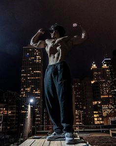 a man standing on top of a wooden platform in front of tall buildings at night