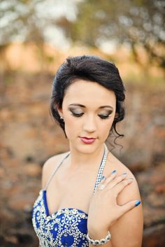 a woman wearing a blue and white dress with pearls on her neck, posing for the camera