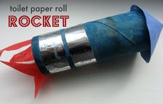 a toilet paper roll rocket is sitting on top of a white surface with red and blue strips