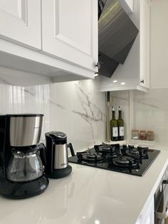 a stove top oven sitting inside of a kitchen next to a bottle of wine and coffee pot