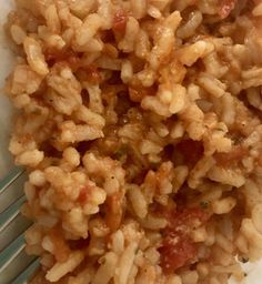 a plate with rice and meat on it next to a fork