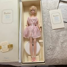 a barbie doll in a box on a bed