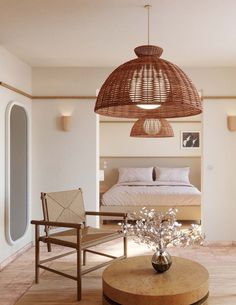 a living room with a bed, chair and table in the middle is lit by a hanging light