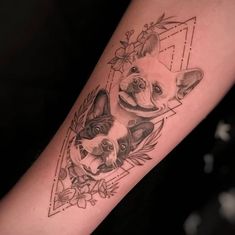 a small dog tattoo on the arm with flowers and leaves around it, in front of a black background