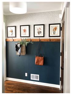 a blue wall with three pictures on the wall and a purse hanging from it's hooks