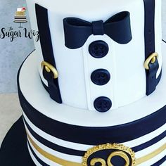 a white and black cake with gold trimmings on it's sides, topped with a bow tie