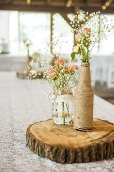 a vase with flowers in it sitting on top of a wooden slice at a table