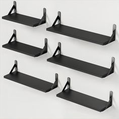 four black shelves with brackets on each one and the other two are hanging from the wall