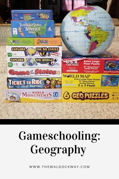 a pile of board games sitting on top of a floor next to a globe and books