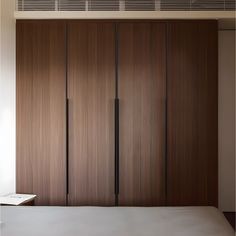 an empty bed in front of wooden closets with sliding doors on the wall and ceiling