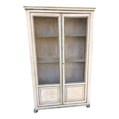 an old white bookcase with glass doors on the front and bottom shelves, against a white background