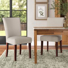 two chairs sitting on top of a rug in front of a wooden table and window