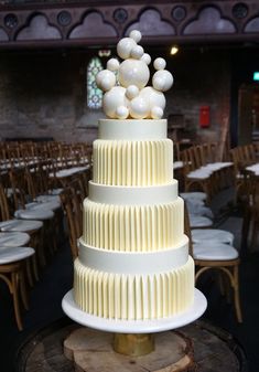 a three tiered cake with white icing and balls on top