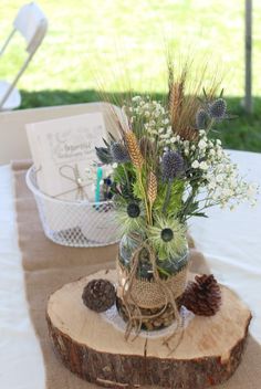 a vase filled with flowers sitting on top of a wooden slice next to a pine cone