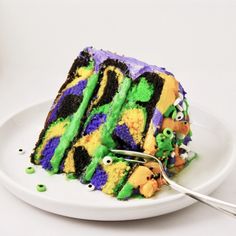 a white plate topped with a piece of cake covered in green and purple frosting