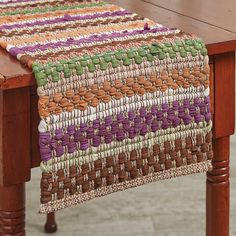 a wooden table with a multicolored woven runner on it