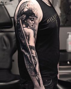 a man with a tattoo on his arm is standing in front of a black and white photo