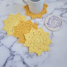 three crocheted coasters and a coffee cup on a marble surface