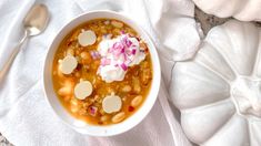 a white bowl filled with beans and sour cream on top of a napkin next to a spoon