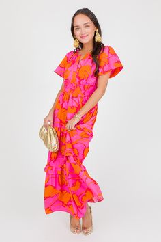 Bright pink covered in bold orange blooms. This maxi features a split neckline, a smocked waistband, a ruffle tiered skirt. Side pockets complete the look. Pull-on fit. Pink Tiered Maxi Dress For Vacation, Pink Tiered Maxi Dress With Smocked Back, Pink Tiered Maxi Dress For Summer, Pink Tiered Skirt Maxi Dress For Summer, Pink Maxi Dress With Smocked Bodice And Tiered Skirt, Pink Dress With Elastic Waistband And Tiered Skirt, Pink Tiered Skirt Dress With Elastic Waistband, Pink Tiered Maxi Dress For Day Out, Pink Tiered Skirt Maxi Dress For Beach